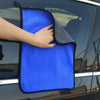 Eine Hand hält ein leuchtend blaues Mikrofasertuch zum Fenster eines Fahrzeugs.