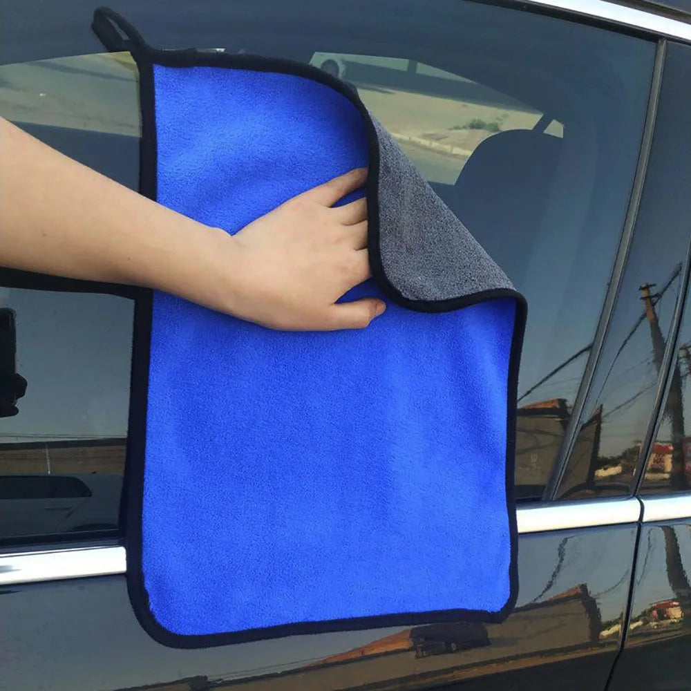 Eine Hand hält ein leuchtend blaues Mikrofasertuch zum Fenster eines Fahrzeugs.