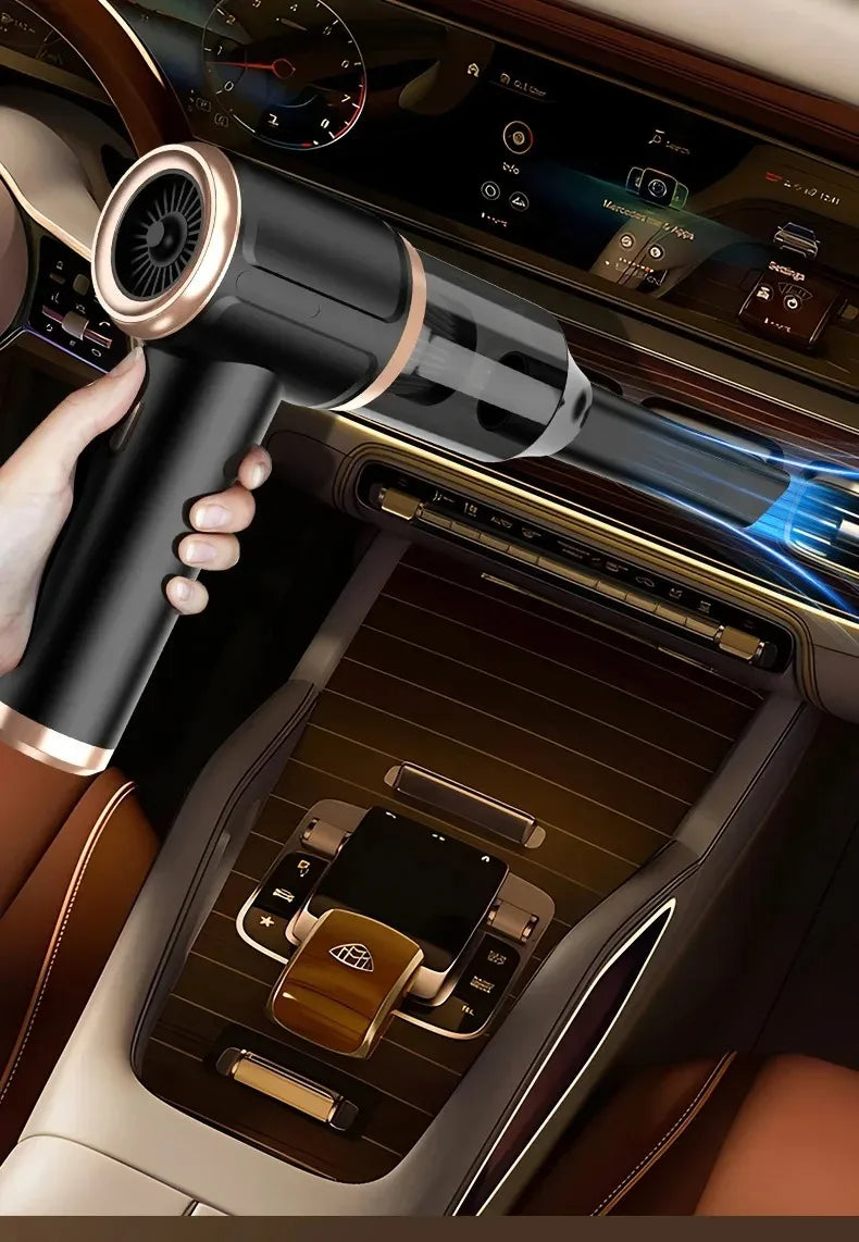 A hand holds a black portable wireless car vacuum device, positioned near a car's interior controls and infotainment screen.
