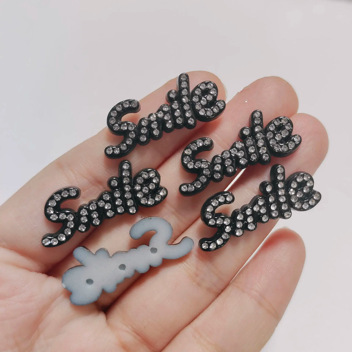 يد تمسك بمجموعة من زينة الكريستال الأسود على شكل كلمتي Side Suite ورقم 2