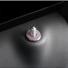 A silver door lock pin trim set with a pink gemstone accent resting on a dark leather surface.