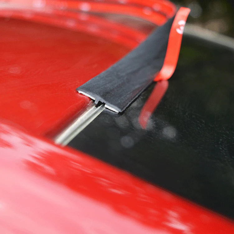 Close-up of a red car roof showing a black sealing strip being applied to the window edge.