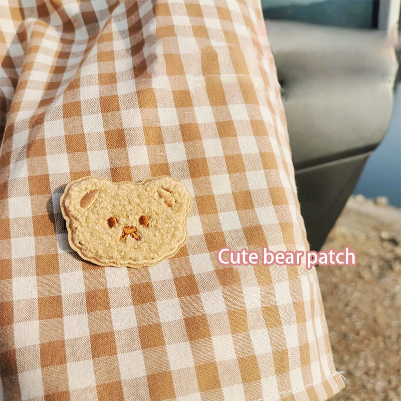 Una tierna huella de oso está colocada sobre tela a cuadros beige y blanco.