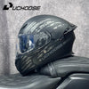 Un casque de moto DOT noir modulaire avec un pare-brise clair posé sur un siège en cuir noir.