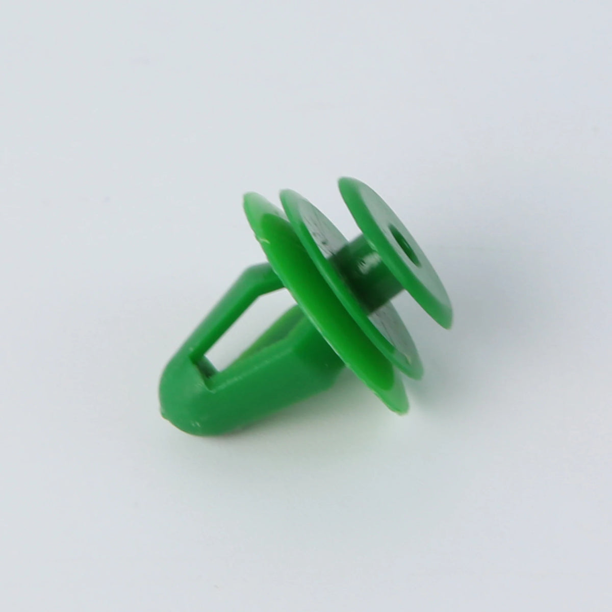 A green universal automotive fastener clip used for trim and bumpers.