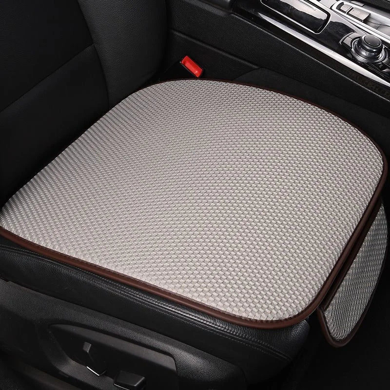 A beige breathable ice silk car seat cushion placed in a black car interior.