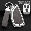 A bright silver grey buckle car key case with a lanyard and multiple keys displayed on a black textured surface.