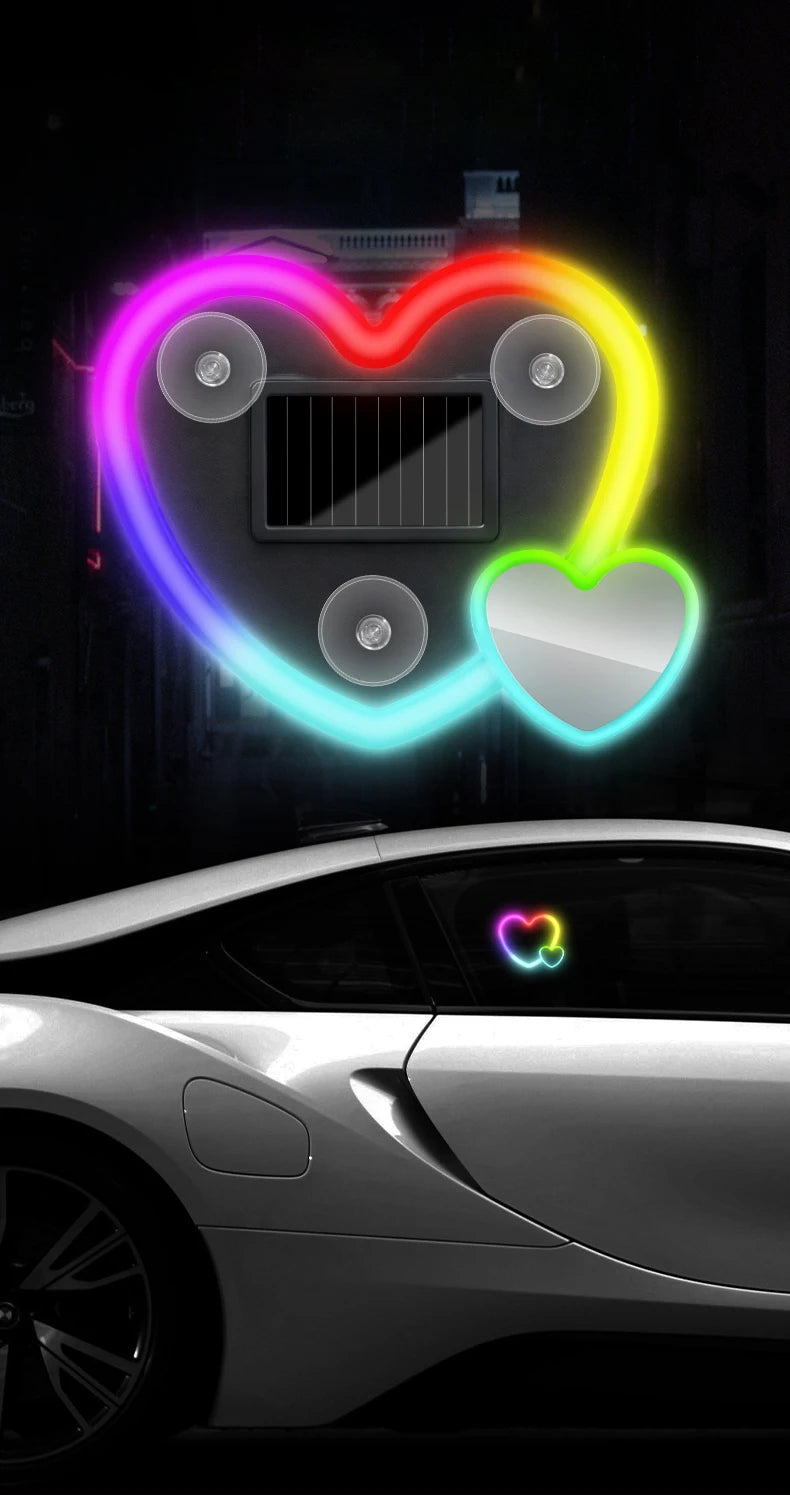 A decorative heart-shaped solar lamp glows with vibrant neon colors above a modern car.