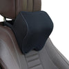 A black memory foam car headrest neck pillow with an adjustable strap resting on a brown leather seat.