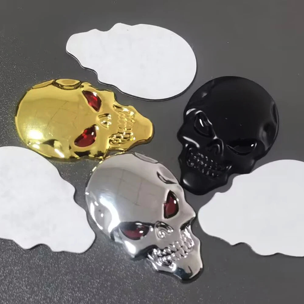 Three chrome skull emblems, gold, black, and silver, are displayed on white cutouts.