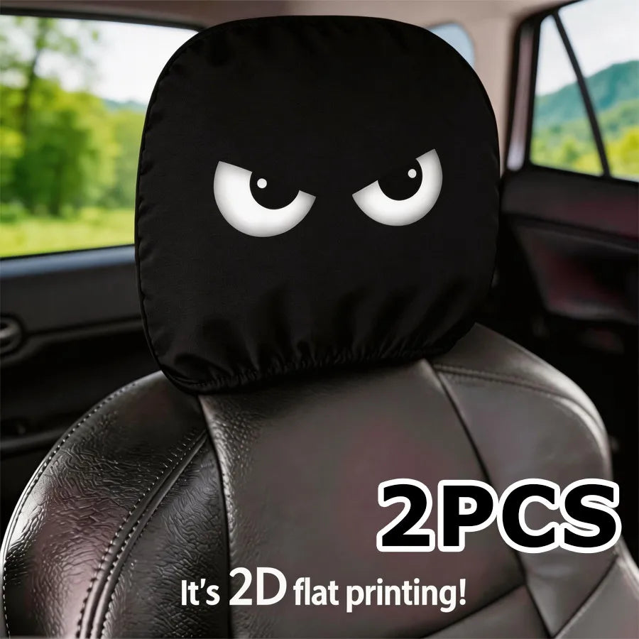 A pair of black angry eyes car headrest covers with 2D flat printing on a leather seat.