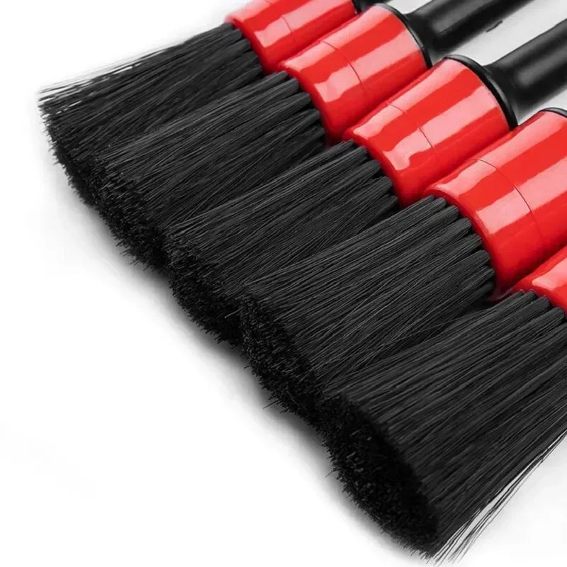 A set of professional car detailing brushes with red and black bristles shown diagonally.