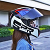 A woman wearing a black and white racing-style ABS motorcycle helmet with blue accents outdoors.