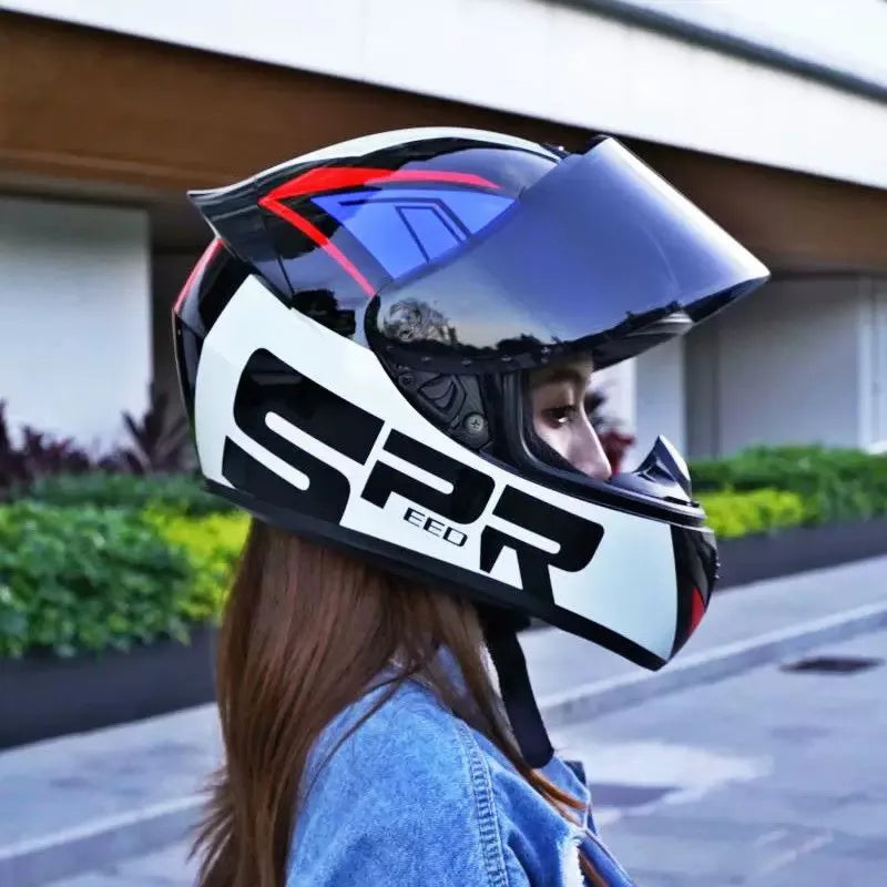 A woman wearing a black and white racing-style ABS motorcycle helmet with blue accents outdoors.