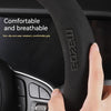 Grip de volant en fibre de carbone noire tenu par une main.
