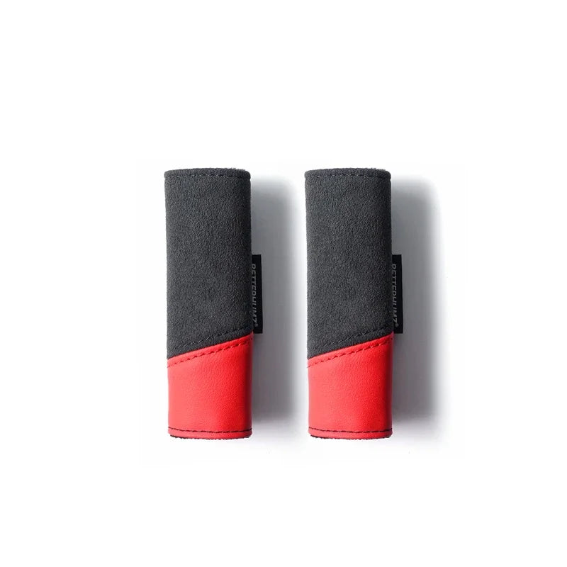 A pair of black and red Alcantara car roof handle covers shown side by side.