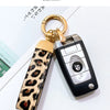 Llavero con anillo dorado y diseño negro y plateado, sujetado por una correa de cuero estampado de leopardo.