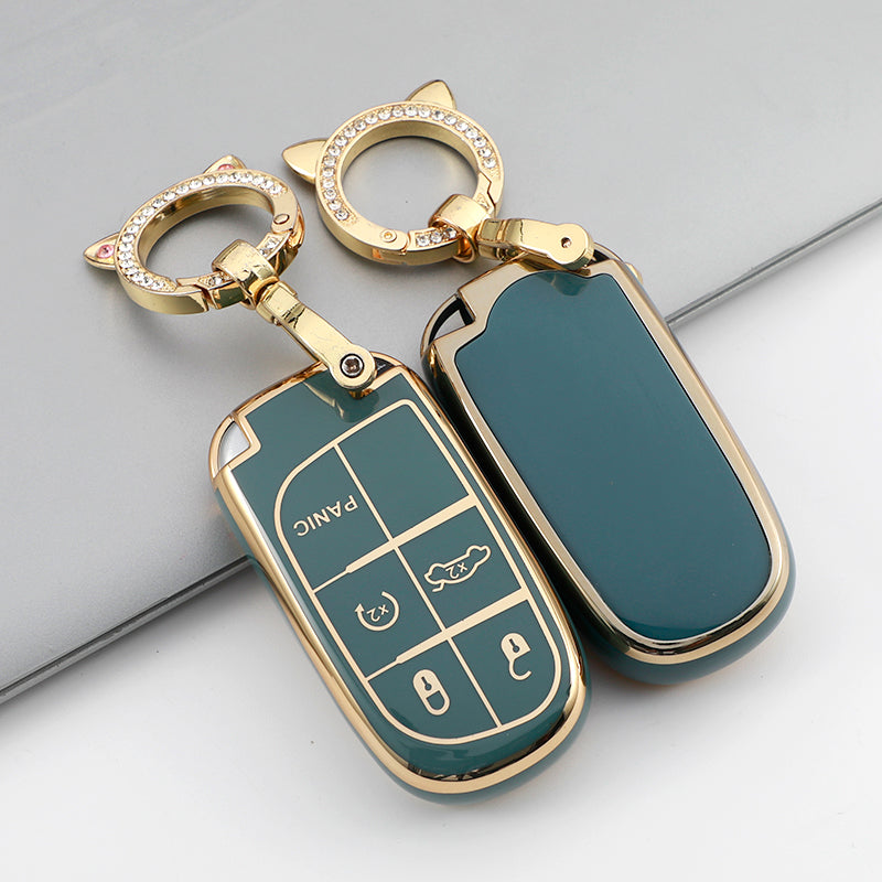 A gold-toned TPU car key case cover with a green finish and a keyring is shown on a gray surface.
