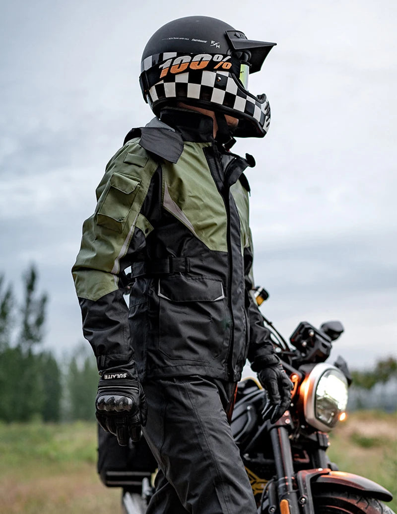 A person wearing a black and white checkered helmet and a dark green waterproof motorcycle jacket is standing outdoors.