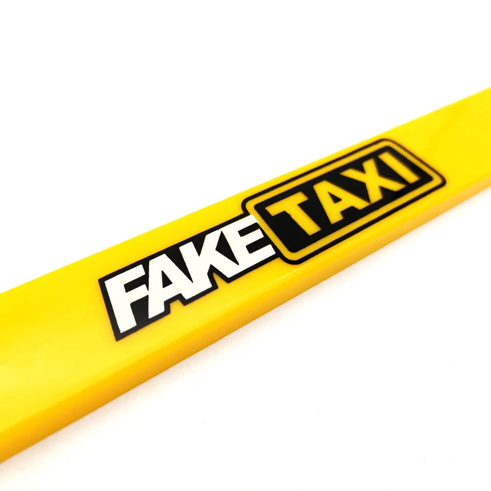 Yellow license plate frame decoration with black text reading FAKE TAXI