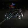 A bicycle with reflective safety stickers on the wheels is parked on a dark road at night.