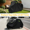 Black waterproof bicycle cover with reflective strips and lock holes placed over a bicycle on a sidewalk.