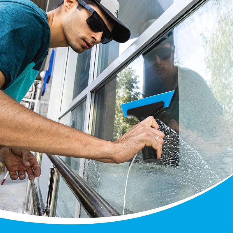 A person uses a professional window tinting tool to apply a film to a glass pane.