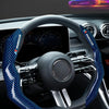 A close-up view of a steering wheel covered in blue carbon fiber material inside a car