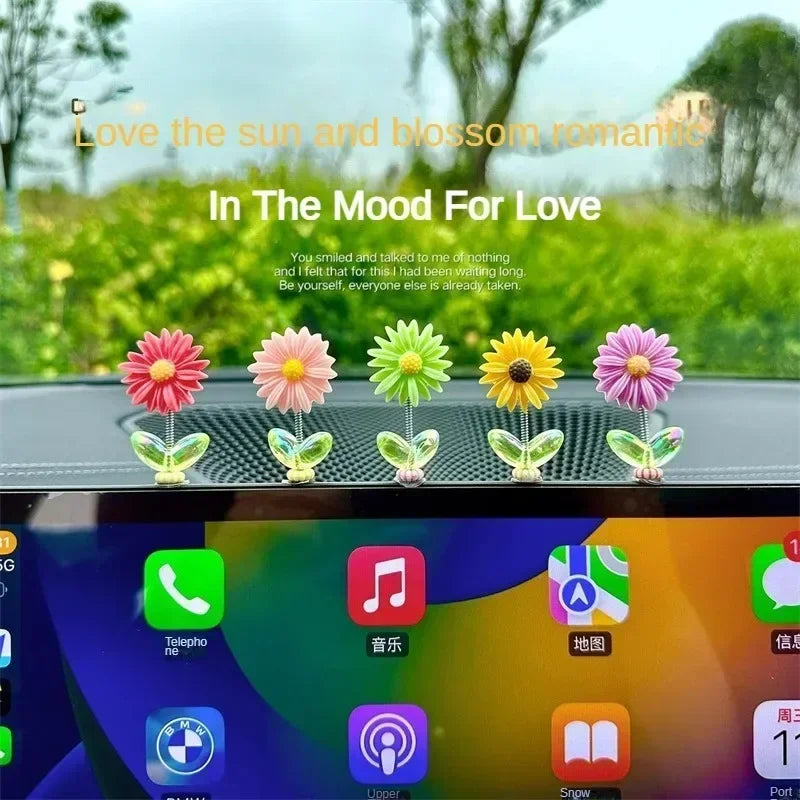Exposition d'ornements de tournesols colorés et tremblants sur une console ou un miroir de voiture.