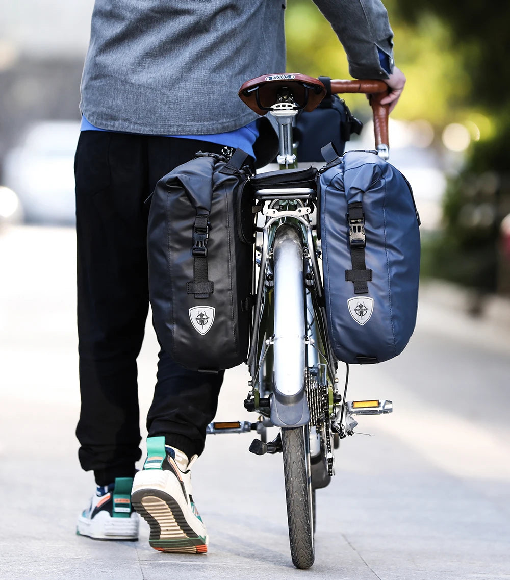 A person is carrying a black foldable waterproof bike pannier bag on a bicycle.