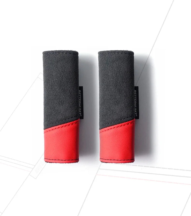 A pair of black and red car roof handle covers made of Alcantara fabric.