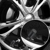 Close-up view of a set of aluminum tire valve caps on a wheel rim.