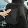 A hand is placing a black car trash organizer with a liner onto the back of a car seat.