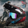 A black and red off-road safety helmet is shown being worn by a rider on a motorcycle in a rugged outdoor setting.