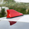 A red shark fin universal car antenna amplifier mounted on a silver car roof.