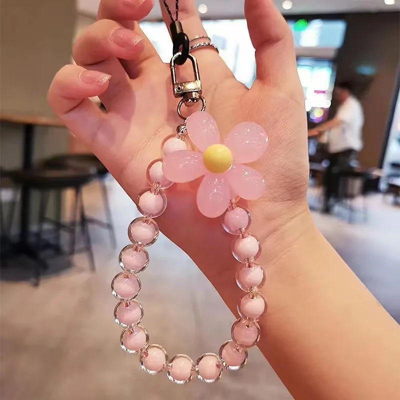 A pink floral bead lanyard pendant with a yellow center is held in a person's hand.
