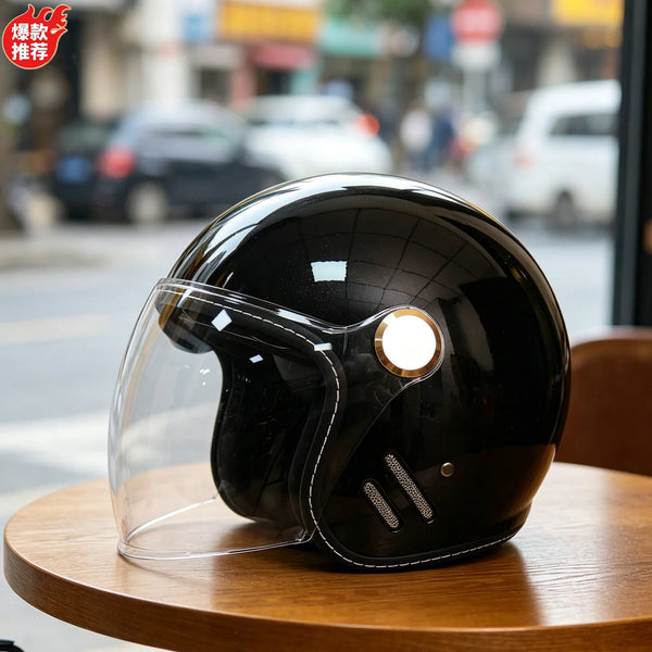 A glossy black two-lens retro motorcycle helmet resting on a wooden table.