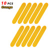 Ten orange reflective safety stickers or tape pieces arranged in a row.