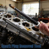 A hand holds a black spark plug removal tool positioned over the cylinder head of an engine.