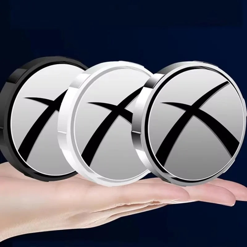 A hand holds three round suction cup blind spot mirrors with rotating lenses.