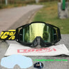 A pair of black motocross goggles with yellow branding resting on a white cloth and a blue lens cover.