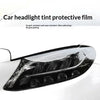 A close-up of a car headlight tinted with a protective film, showing a clear, dark lens on a white vehicle.
