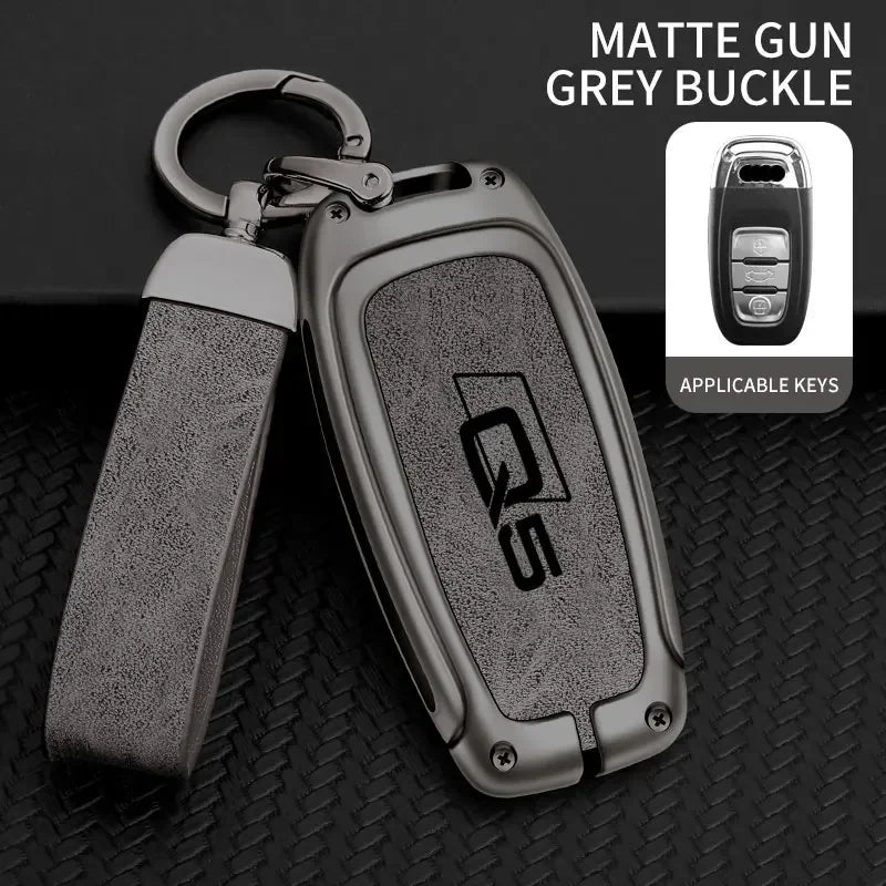 A matte grey buckle key fob cover for an Audi Q5, shown with an applicable key.