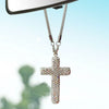 A sparkling stainless steel cross pendant hanging from a chain, displayed against a bright blue sky.