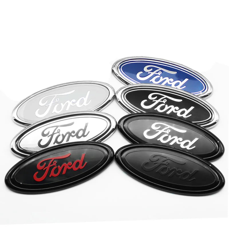 A collection of five oval Ford emblem badges or stickers in silver, blue, and black finishes.