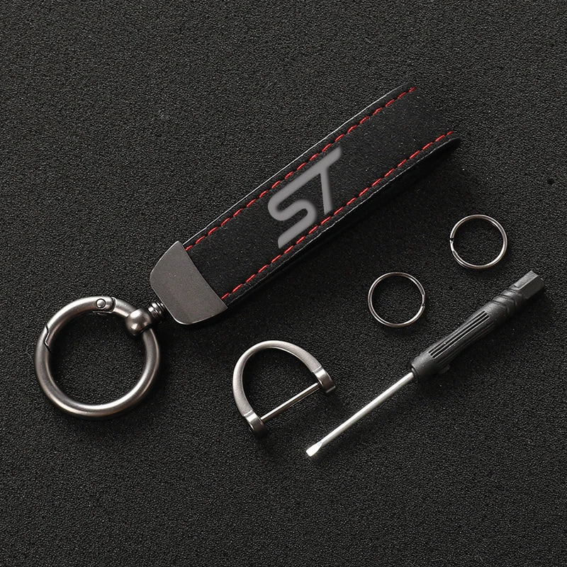 A black suede leather car keychain featuring a silver ring and a metal tool.