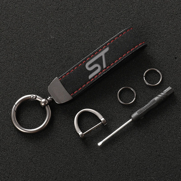 A black suede leather car keychain featuring a silver ring and a metal tool.