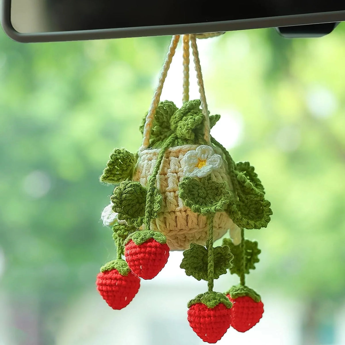 A handmade strawberry crochet hanging decor featuring red strawberries and green leaves, suspended from a string.