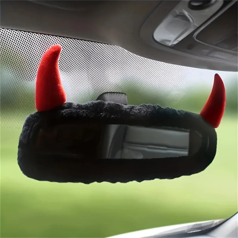 Décor de miroir noir avec des cornes de diable rouges fixé sur le rétroviseur d'une voiture.