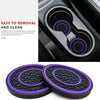 A set of two black silicone car cup holder coasters with purple accents shown next to a car interior component.